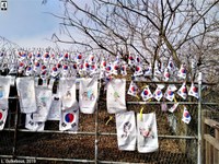 Drapeaux sud-coréens et messages et dessins en faveur d’une réunification des deux Corées, déposés sur une clôture et des barbelés